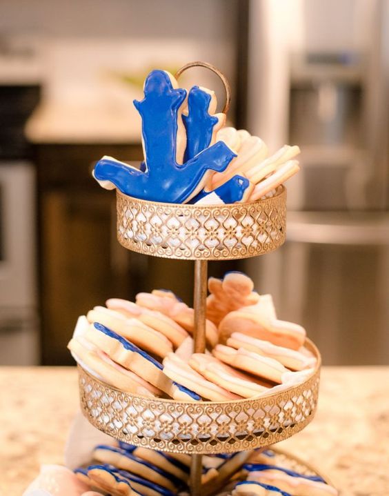 a chic stand with anchor shaped cookies in blue and white is a cool dessert idea for a nautical bridal shower