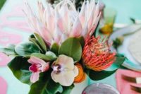 a chic tropical bridal shower centerpiece with orchids and proteas plus greenery