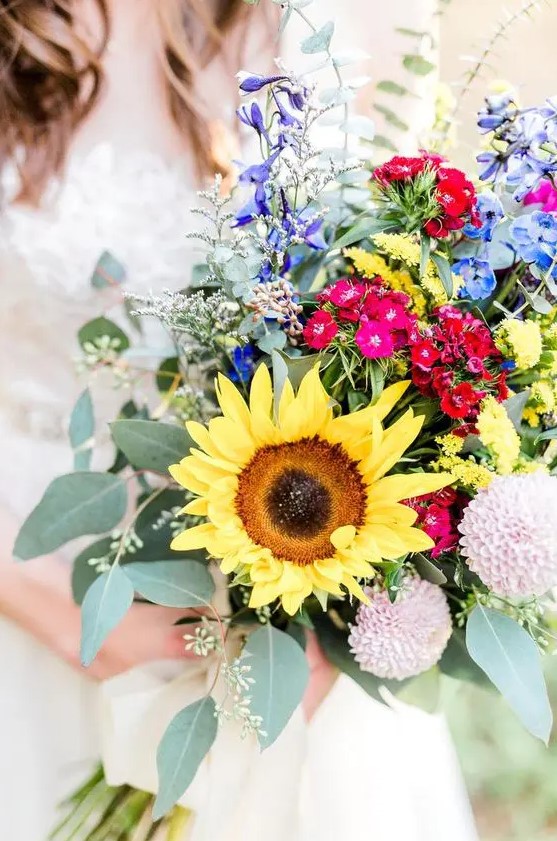 a colorful sunflower wedding bouquet with purple, blue, pink, red and blush blooms including dahlias, greenery and large sunflowers is amazing for a summer bride
