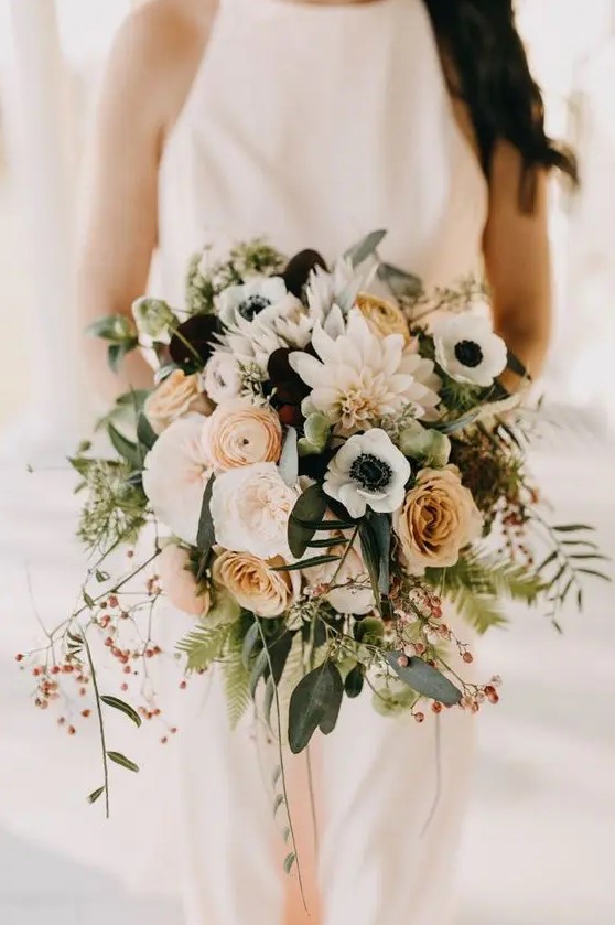 a cool wedding bouquet of rust roses and ranunculus, dark blooms, white anemones and dahlias, greenery and berries