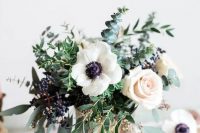 a cool wedding centerpiece of blush roses, white anemones, greenery, privet berries and a cool vase is ideal for spring or summer