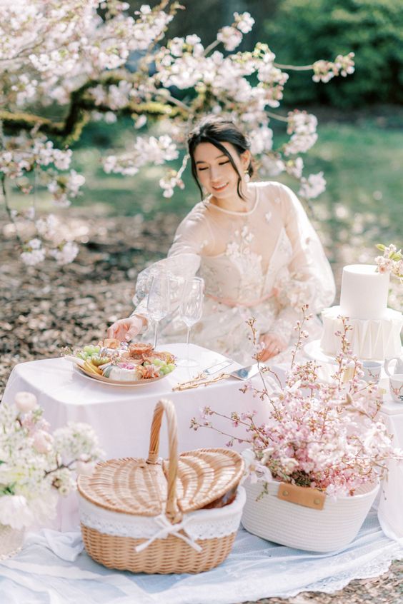 a couple's picnic with cherry blossom, a small grazing table and wine plus a neutral wedding cake is a great idea for a spring elopement