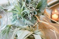 a creative wedding centerpiece of pale greenery, air plants and driftwood is a stylish idea fro a modern coastal wedding