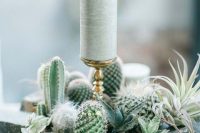 a creative wedding centerpiece of rocks, cacti and succulents, pillar candles is a lovely idea for a boho wedding