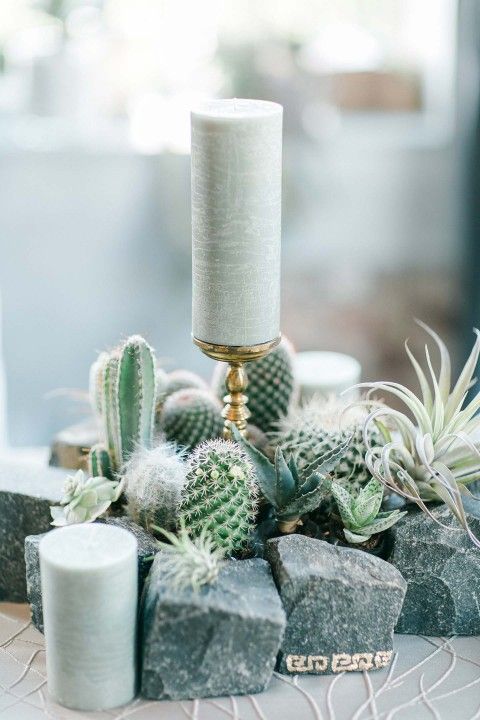 a creative wedding centerpiece of rocks, cacti and succulents, pillar candles is a lovely idea for a boho wedding