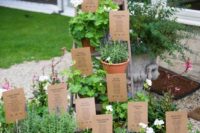 a creative wedding seating chart made of a ladder and crates and potted greenery plus cardboard with tables