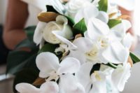 a creative white orchid and rose wedding bouquet with foliage and magnolia leaves