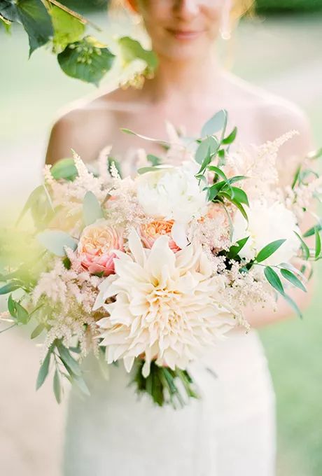 a delicate pastel wedding bouquet of white and blush dahlias, blush peony roses and astilbe, greenery for a spring or summer bride