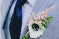 a delicate spring boutonniere of a white anemone, a pink blooming branch and some greenery is lovely