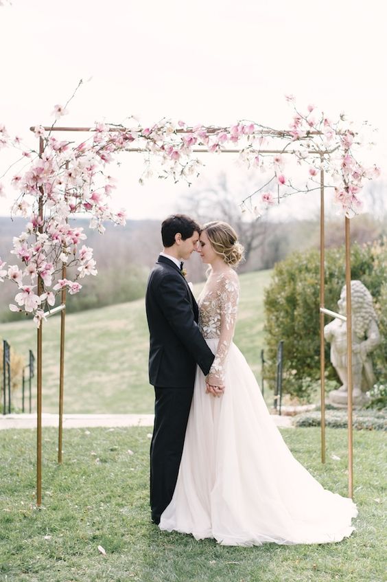 a delicate wedding arch with a bit of pink cherry blossom is a gorgeous idea for a subtle spring wedding