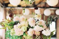 a delicate wedding centerpiece of blush dahlias, deep purple blooms and greenery for a summer wedding