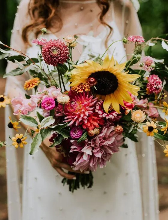 a dreamy summer wedding bouquet with pink, blush, orange blooms including dahlias and sunflowers plus some foliage is a cool idea for a relaxed summer bride