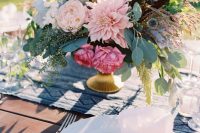 a fantastic wedding centerpiece of pink dahlias, peony roses, greenery, allium and feathers for a summer wedding