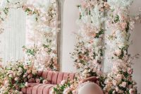 a fantastic wedding photo zone with a pink sofa, pink and white cherry blossom and greeneyr and macaron-inspired poufs