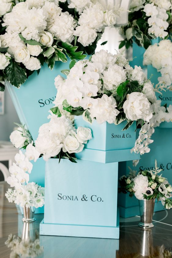 a fun bridal shower decor idea with tiffany blue boxes, white roses, greenery and little vases with blooms