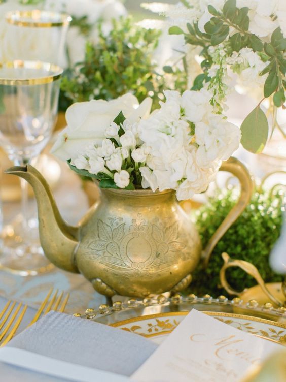 a gilded teapot with neutral blooms and greenery is a chic vintage and elegant wedding centerpiece