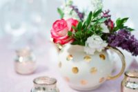 a gold polka dot teapot with pink, purple and white blooms and silver candle holders