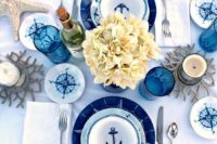 a gorgeous nautical shower tablescape with navy and blue plates, neutral blooms, compasses, starfish and blue glasses