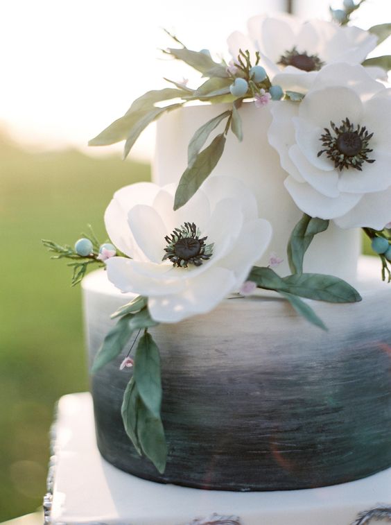 a grey and white wedding cake with anemones and greenery on top is a stylish idea for a modern wedding