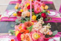 a hot pink bridal shower tablescape with hot pink placemats, bright florals, pink candles, gold cutlery