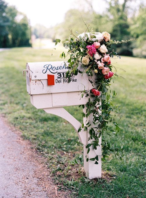 a large vintage mailbox on a stand decorated with greenery and fresh blooms is classics to meet your guests