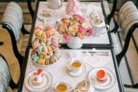 a lovely and inviting Parisian bridal shower tablescape with bold blooms, lots of delicious sweets and tea is a gorgoeus idea