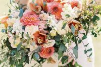 a lovely and lush wedding bouquet with blush and white roses, pink and orange dahlias, lilies and lots of greenery for a summer wedding