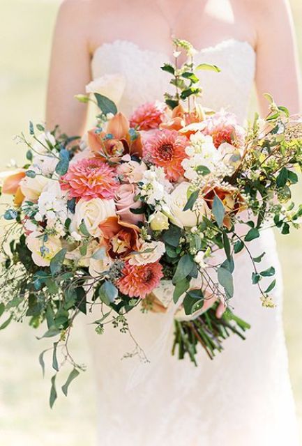 a lovely and lush wedding bouquet with blush and white roses, pink and orange dahlias, lilies and lots of greenery for a summer wedding