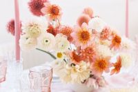 a lovely wedding centerpiece of pink and orange dahlias, white ranunculus and dahlias and some pink candles