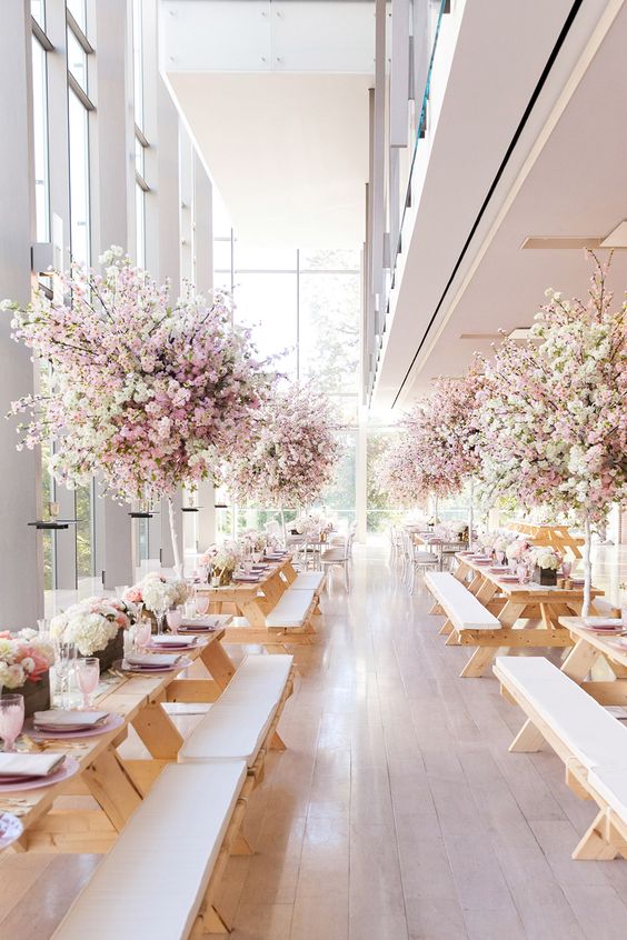 a lovely wedding reception space wiht lush cherry blossom wedding centerpieces and light pink napkins is amazing