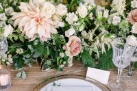 a neutral wedding centerpiece of greenery, white garden roses, blush dahlias and roses and some neutral fillers