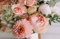 a pastel wedding bouquet of blush roses and dahlias, white peonies, greenery, white and pink astilbe and a neutral wrap