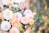 a pastel wedding bouquet of pink and orange dahlias, lilac and orange blooms and ranunculus, greenery for a delicate pastel summer wedding