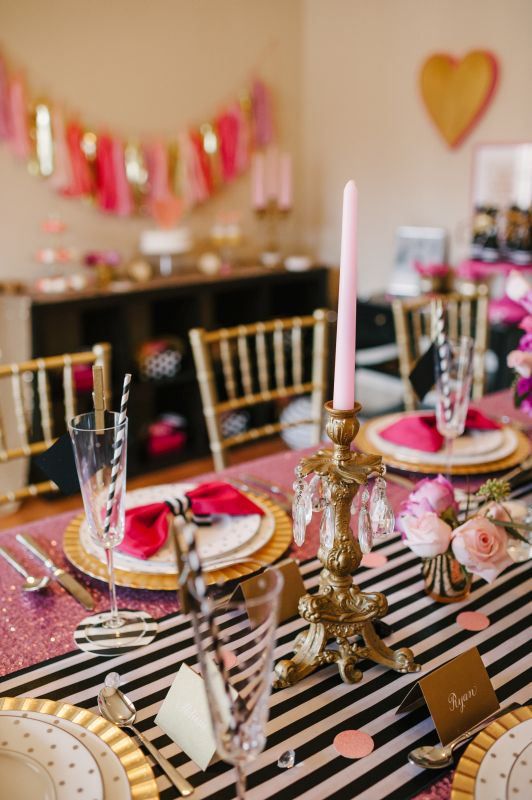 a pink Parisian inspired bridal shower table with a pink sequin tablecloth, a striped runner, pink candles and pink blooms, gold chargers and cutlery
