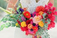 a pretty and bright wedding bouquet with red, blush, yellow and orange blooms including dahlias and ranunculus, greenery and fillers that add dimension