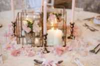 a pretty spring wedding tablescape with pink cherry blossom and petals, tall and thin blush candles and gold touches