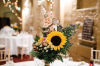 a quirky rustic wedding centerpiece of a wood slice, some jars with petals, a sunflower arrangement and some burlap