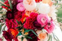 a refined and bold wedding bouquet with red, purple, pink, blush and yellow blooms including dahlias, ranunculus and some greenery and berries