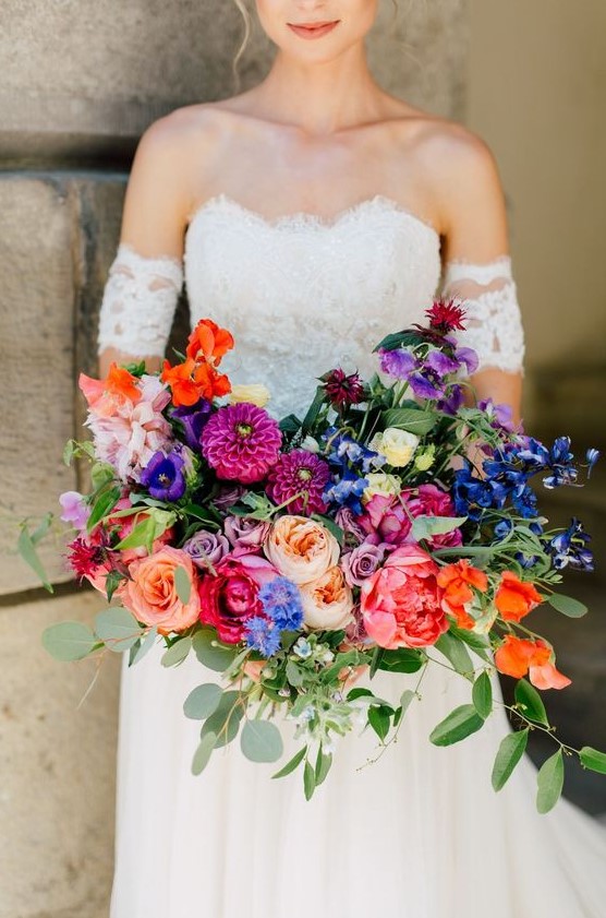 a refined wedding bouquet with pink, red, fuchsia, purple and blue blooms and foliage is a lovely idea for a colorful wedding