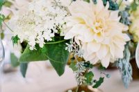 a refined white wedding centerpiece of white blooms including dahlias, greenery and berries is a lovely idea for a neutral wedding