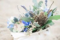 a seashell decoration with fresh blue blooms, greenery and thistles is a cute idea of a bridal shower centerpiece