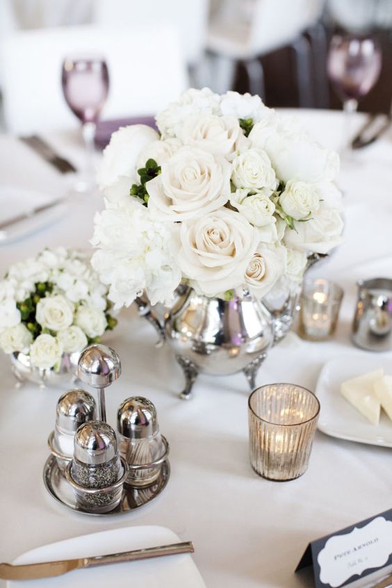 a silver teapot with white roses and mercure glass candle holders is pure elegance
