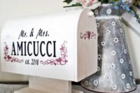 a simple and cute white mailbox with the names and some pink and white hearts plus fresh blooms in a jug