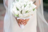 a simple and minimal white tulip wedding bouquet with a white silk wrap is a timeless idea for every bride