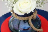 a simple and stylish centerpiece with a red and blue charger, a blue vase with rope and white roses and baby’s breath