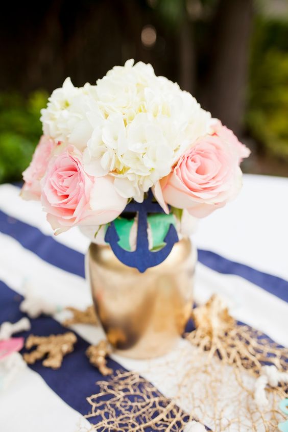 a simple bridal shower centerpiece with a gilded vase, a navy anchor, neutral and pink blooms plus net