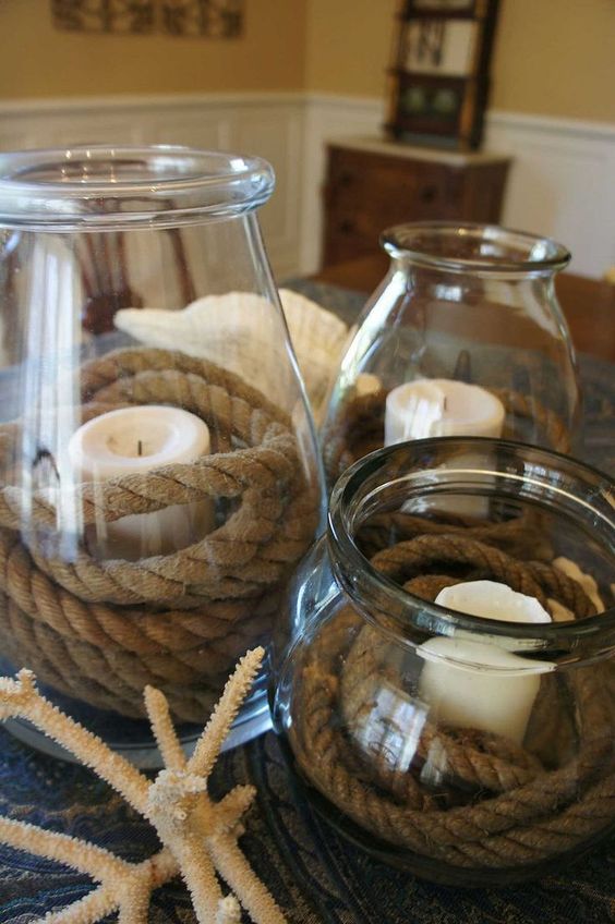 a simple centerpiece with large jars and candles wrapped with rope and coral and shells for a nautical bridal shower