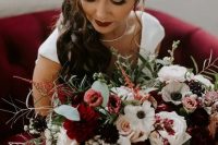 a statement fall wedding bouquet of burgundy blooms, rust roses, white anemones and peonies, greenery and dark blooms