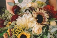 a stylish fall wedding bouquet of sunflowers, burgundy and peachy blooms and much textural greenery