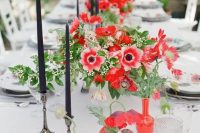 a super colorful wedding centerpiece of red anemones and greenery paired with black candles and red vases is wow